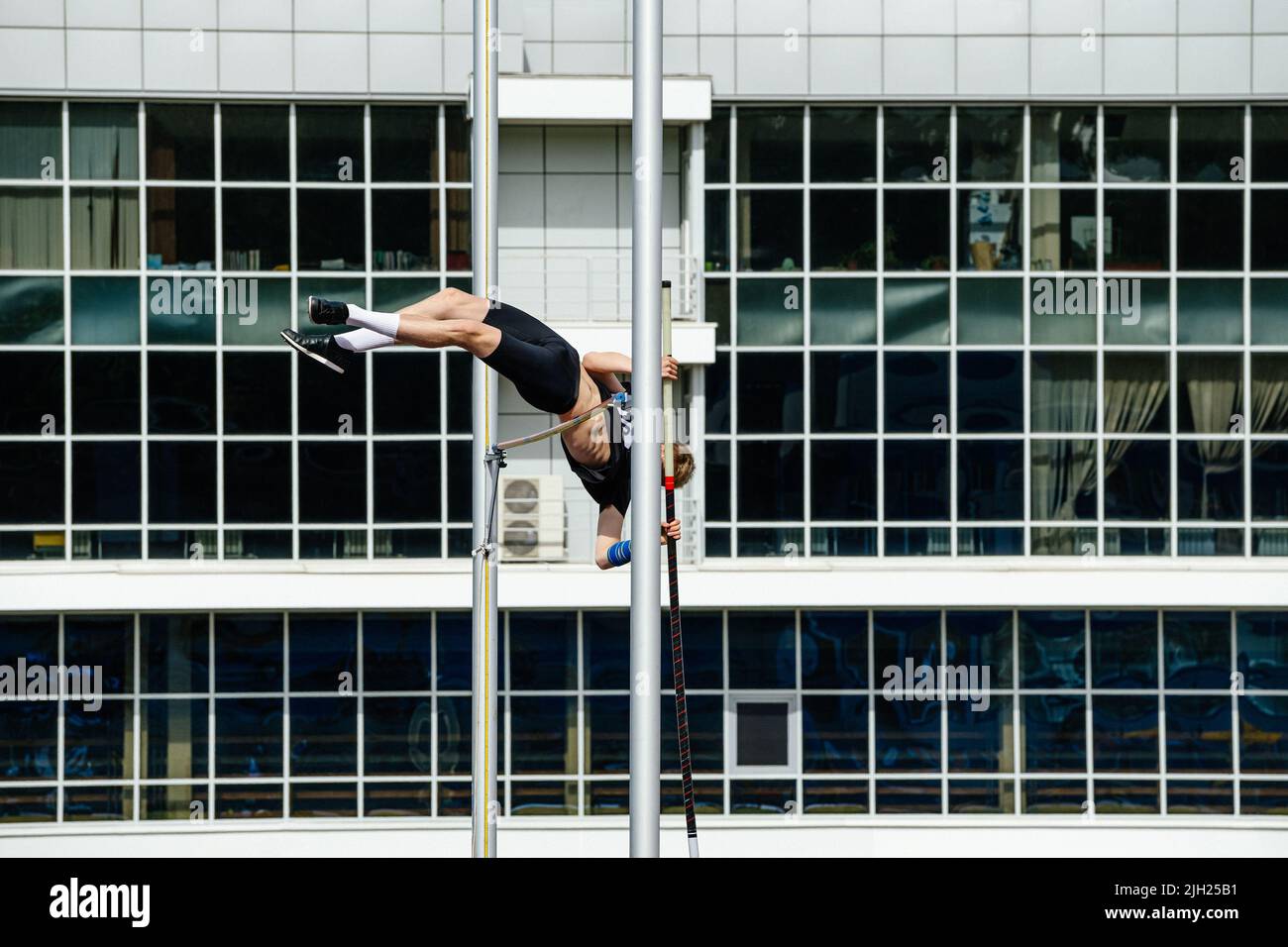 saut à la perche d'athlète masculin sur fond de bâtiment Banque D'Images