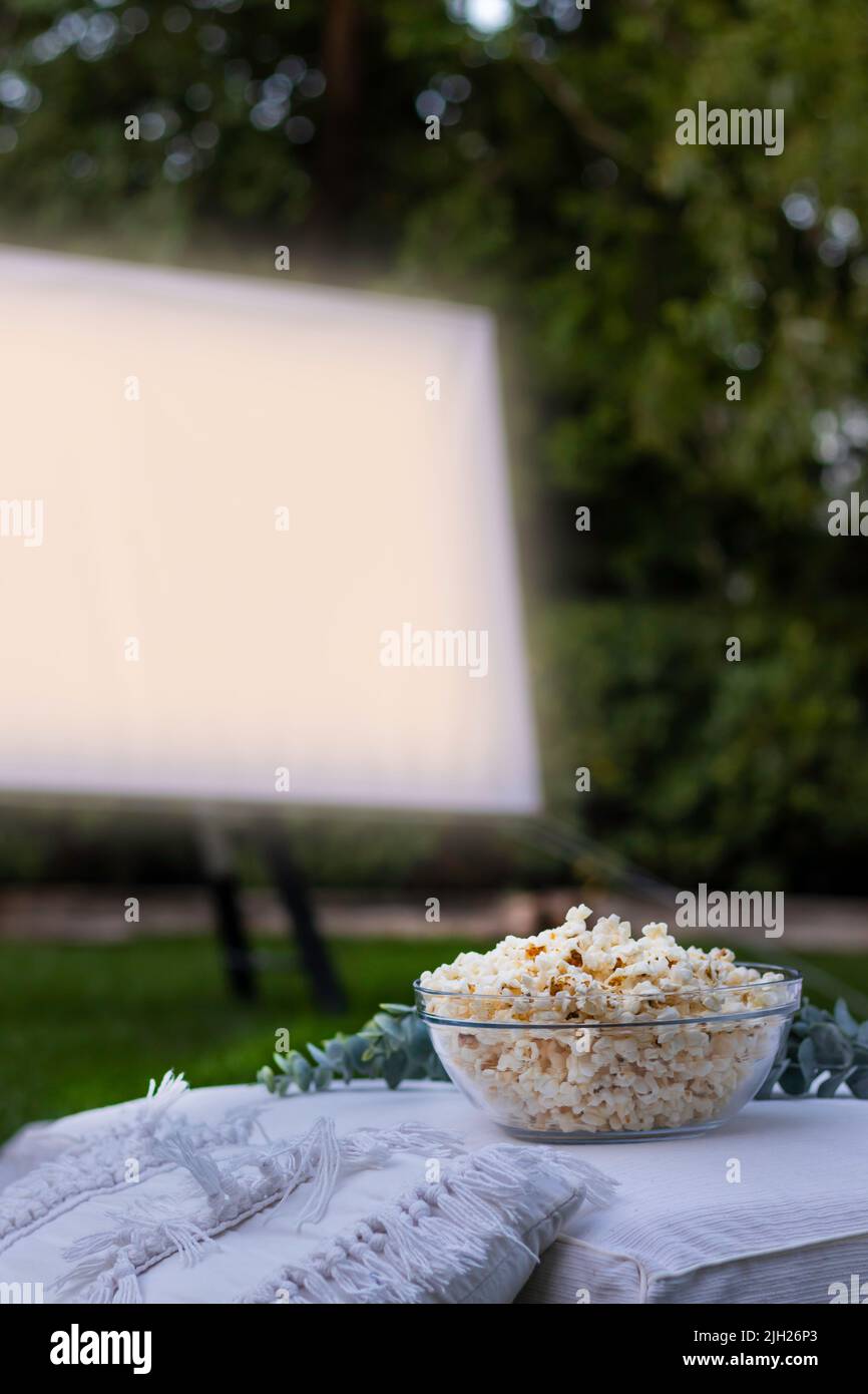 Vue verticale d'un bol de pop-corn isolé et d'un écran de projection en arrière-plan pour regarder un film dans le parc la nuit Banque D'Images