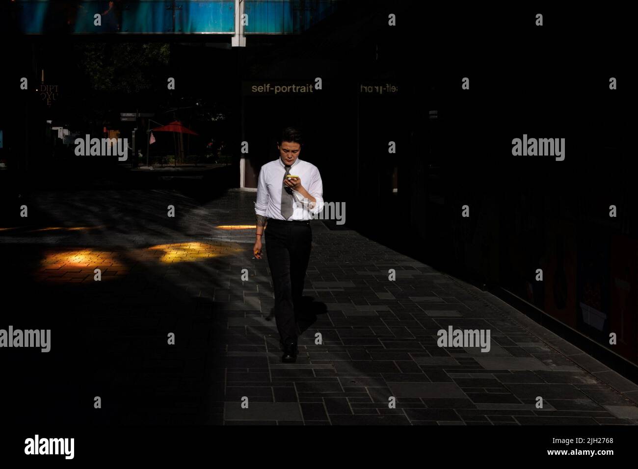 Un homme regarde son téléphone alors qu'il marche dans un quartier commerçant de Pékin, Chine, 14 juillet 2022. REUTERS/Thomas Peter Banque D'Images