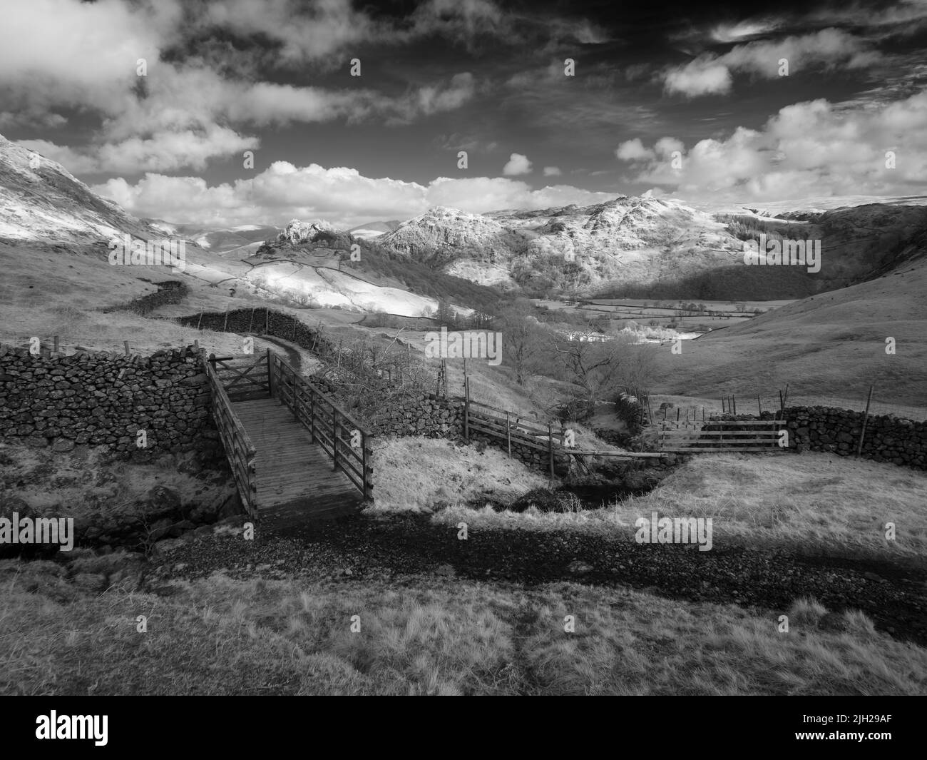 Une image infrarouge d'un pont au-dessus de Scaleclose Gill avec Castle Crag et Grange est tombée au-delà de Borrowdale dans le parc national de Lake District, Cumbria, Angleterre. Banque D'Images