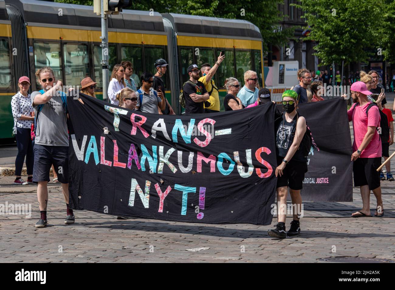 nyt transvallankumous ! Personnes tenant une bannière à la parade Helsinki Pride 2022 à Mannerheimintie, Helsinki, Finlande. Banque D'Images