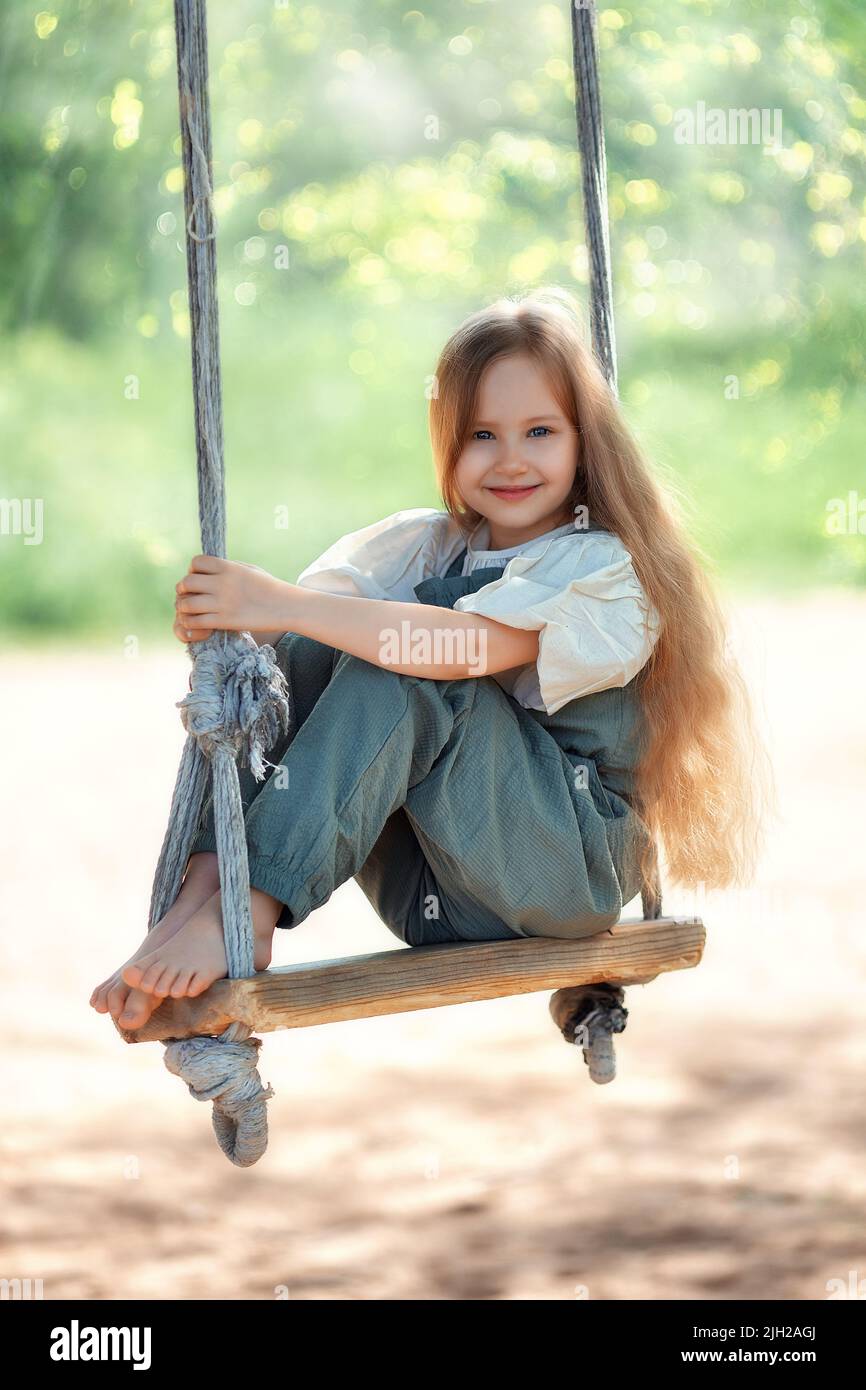 Joyeux rire petite fille avec de longs cheveux en profitant d'une promenade d'oscillation sur une journée ensoleillée d'été Banque D'Images