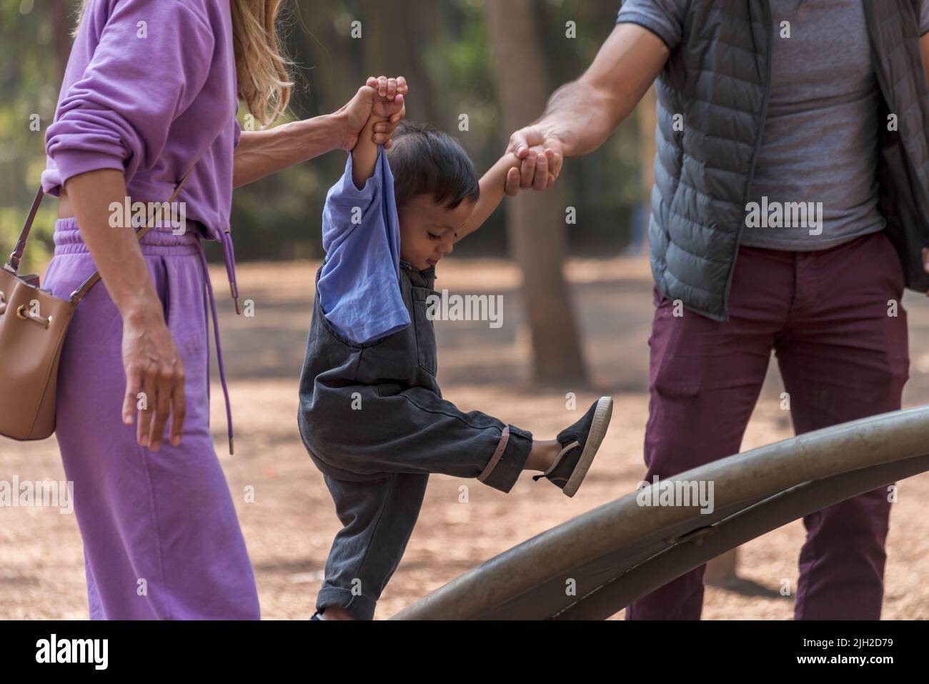 Couple latin aidant leur bébé garçon à monter une rampe tenant les mains Banque D'Images