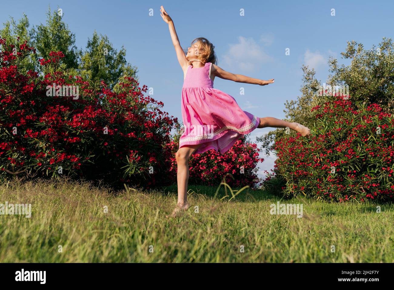 Une fille saute dans le parc sur l'herbe. Banque D'Images