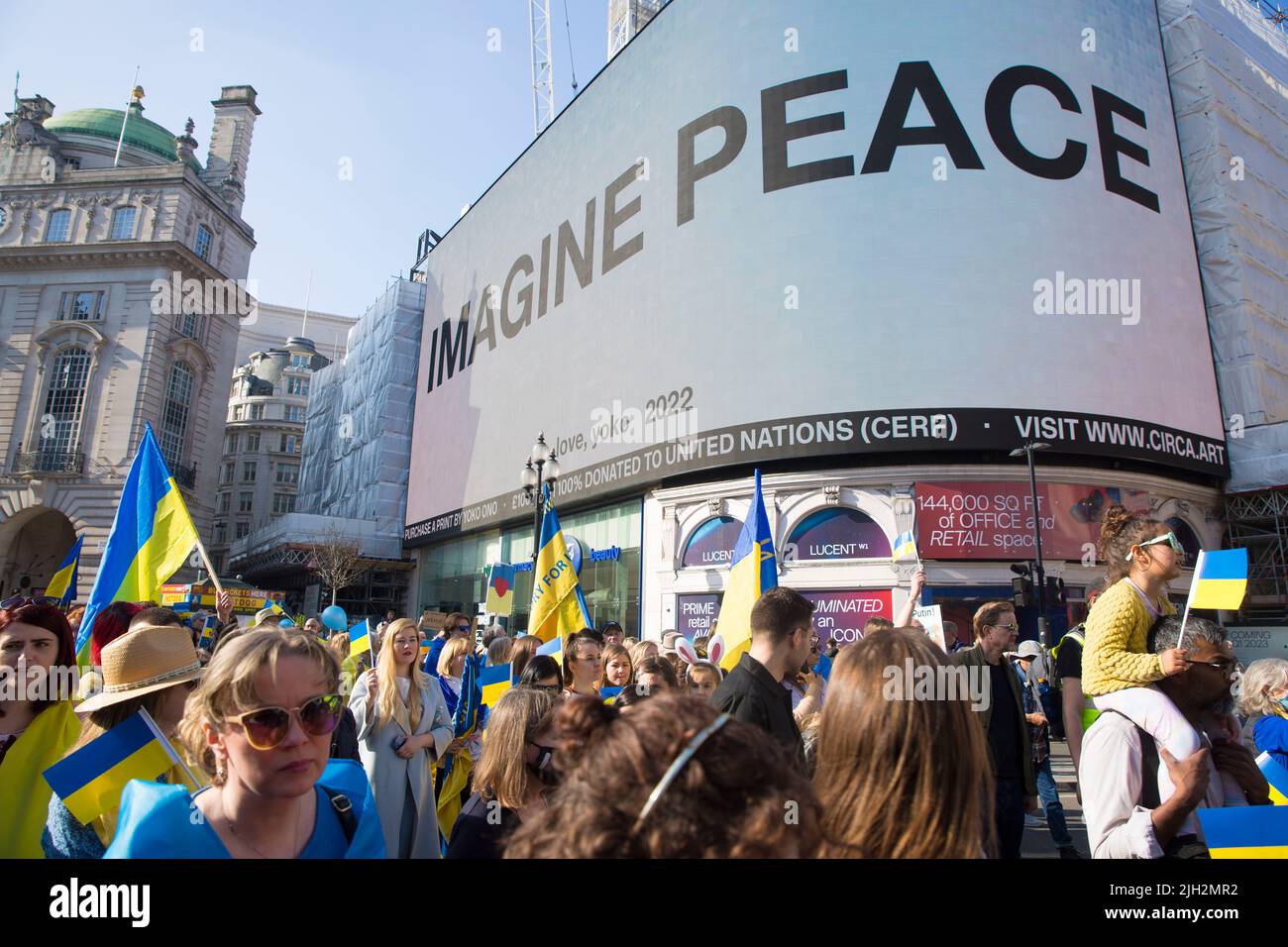 «IMAGINEZ LA PAIX», un message de Yoko Ono est affiché sur le grand panneau électrique alors que les gens défilent pendant la marche «Londres se tient avec l'Ukraine». Banque D'Images
