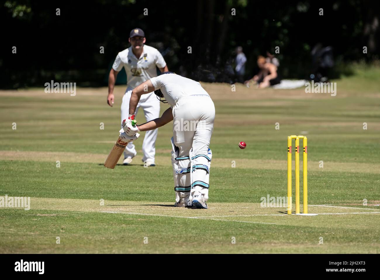 Le batteur dirige le ballon vers le côté de la jambe, sous la surveillance d'un proche batteur lors d'un match de cricket dans un village à Huddersfield, dans le Yorkshire, en Angleterre Banque D'Images