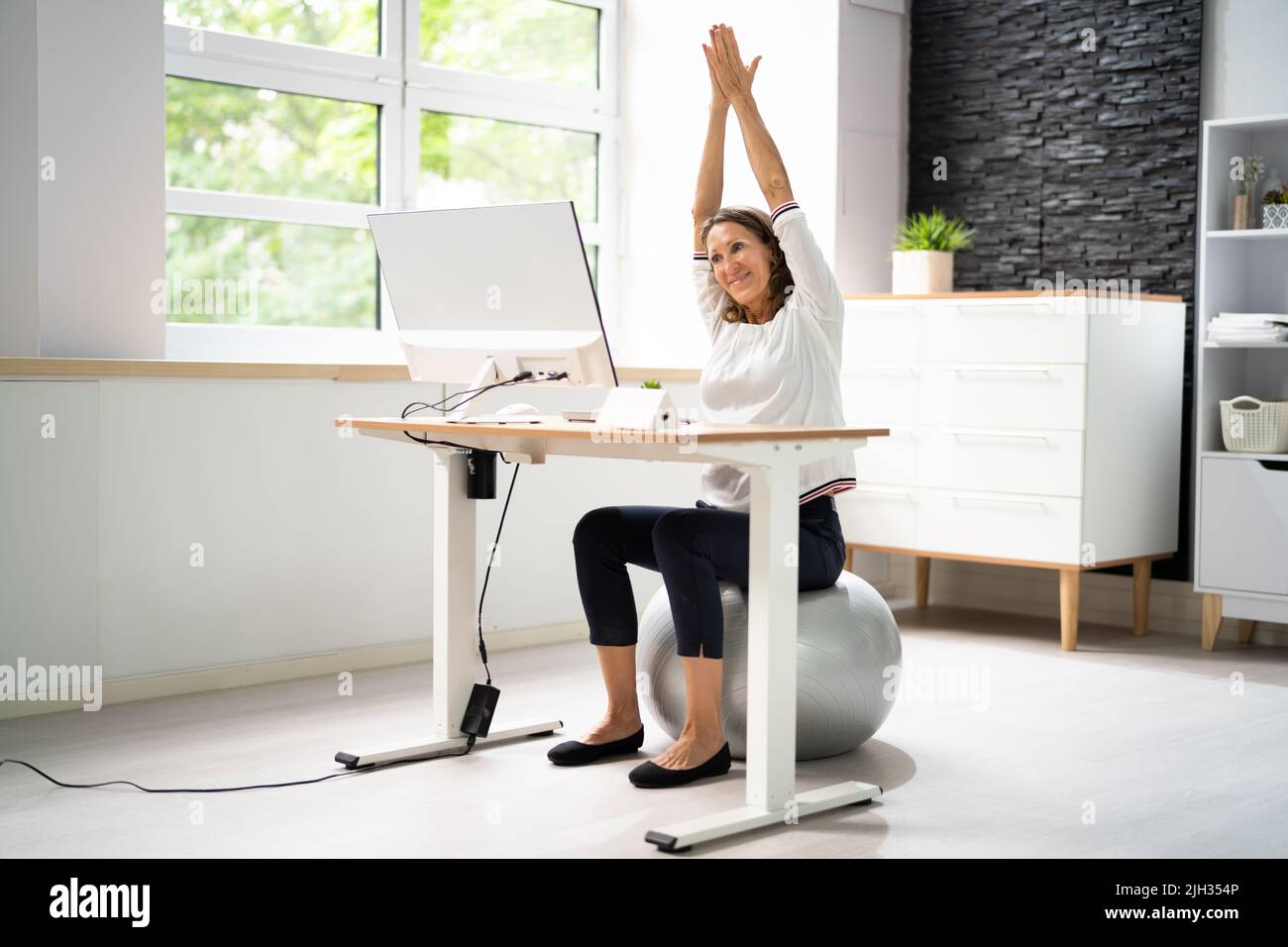 Gros plan d'Une femme d'affaires heureuse se détendant sur un ballon de fitness au bureau Banque D'Images