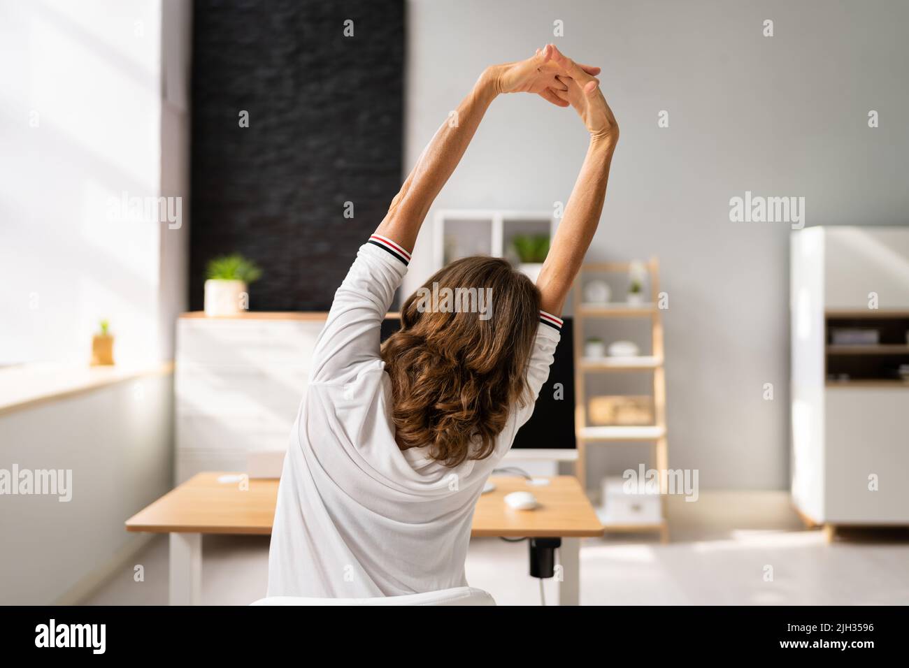 Close-up of a young woman Stretching Her Arms sur le lieu de travail Banque D'Images