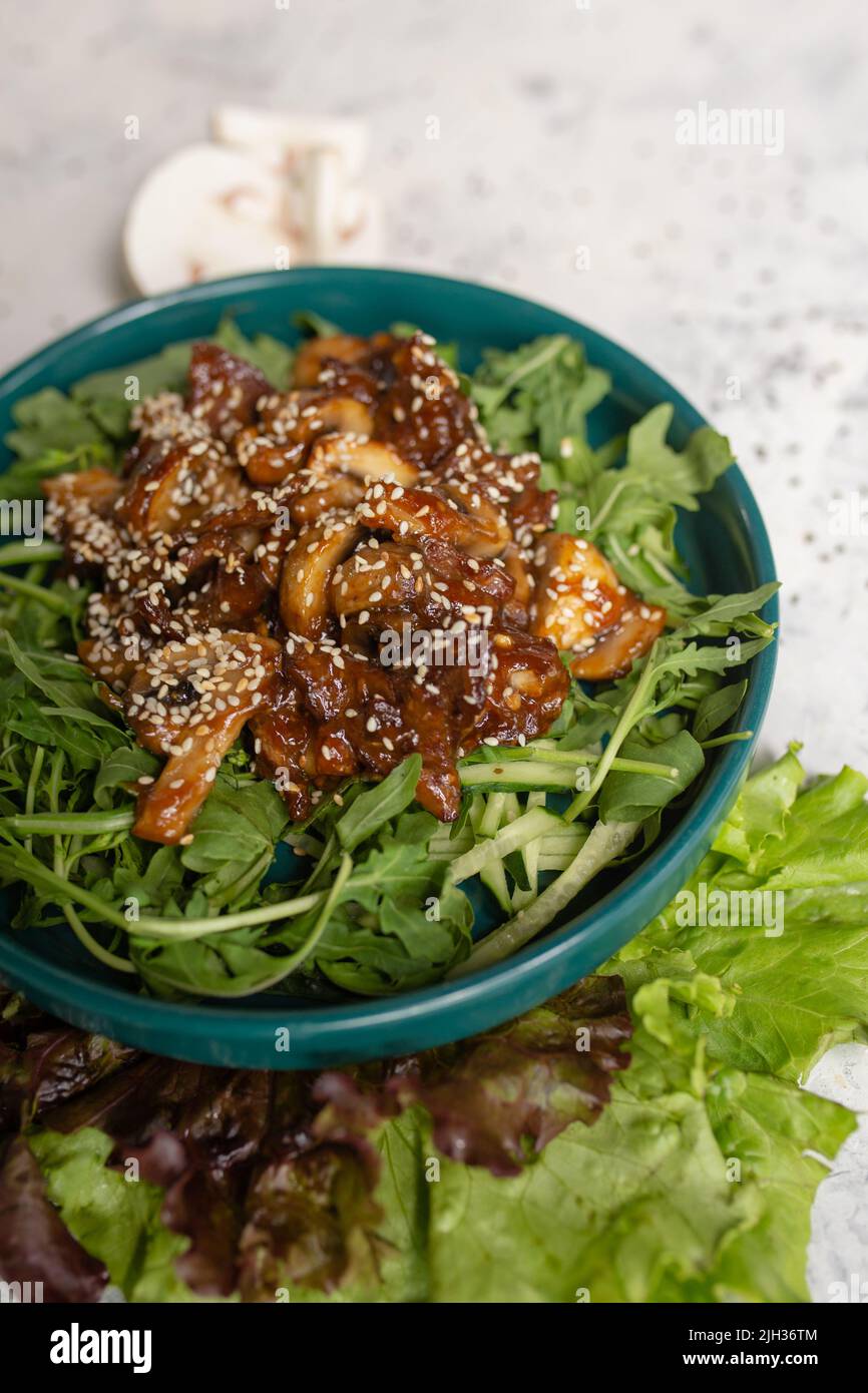 salade chaude avec champignons et arugula gros plan sur un fond clair. Banque D'Images