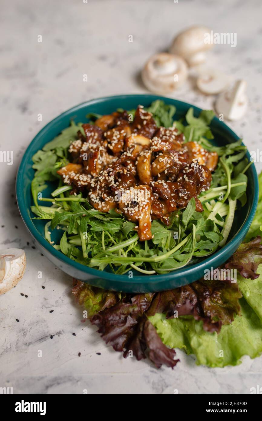 salade chaude avec champignons et arugula gros plan sur un fond clair. Banque D'Images