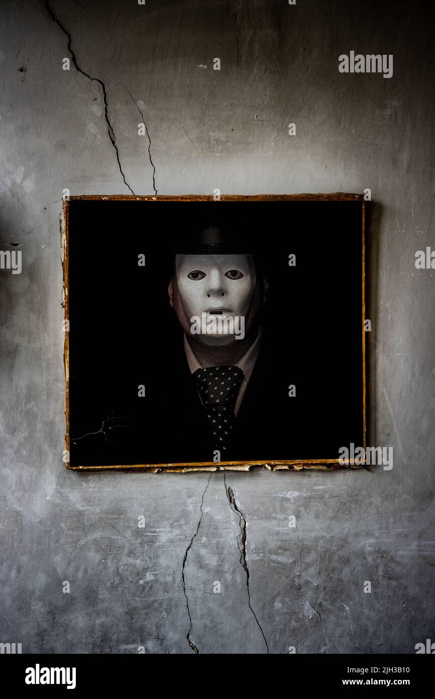 Une peinture d'un homme masqué est suspendue sur un mur brisé Banque D'Images
