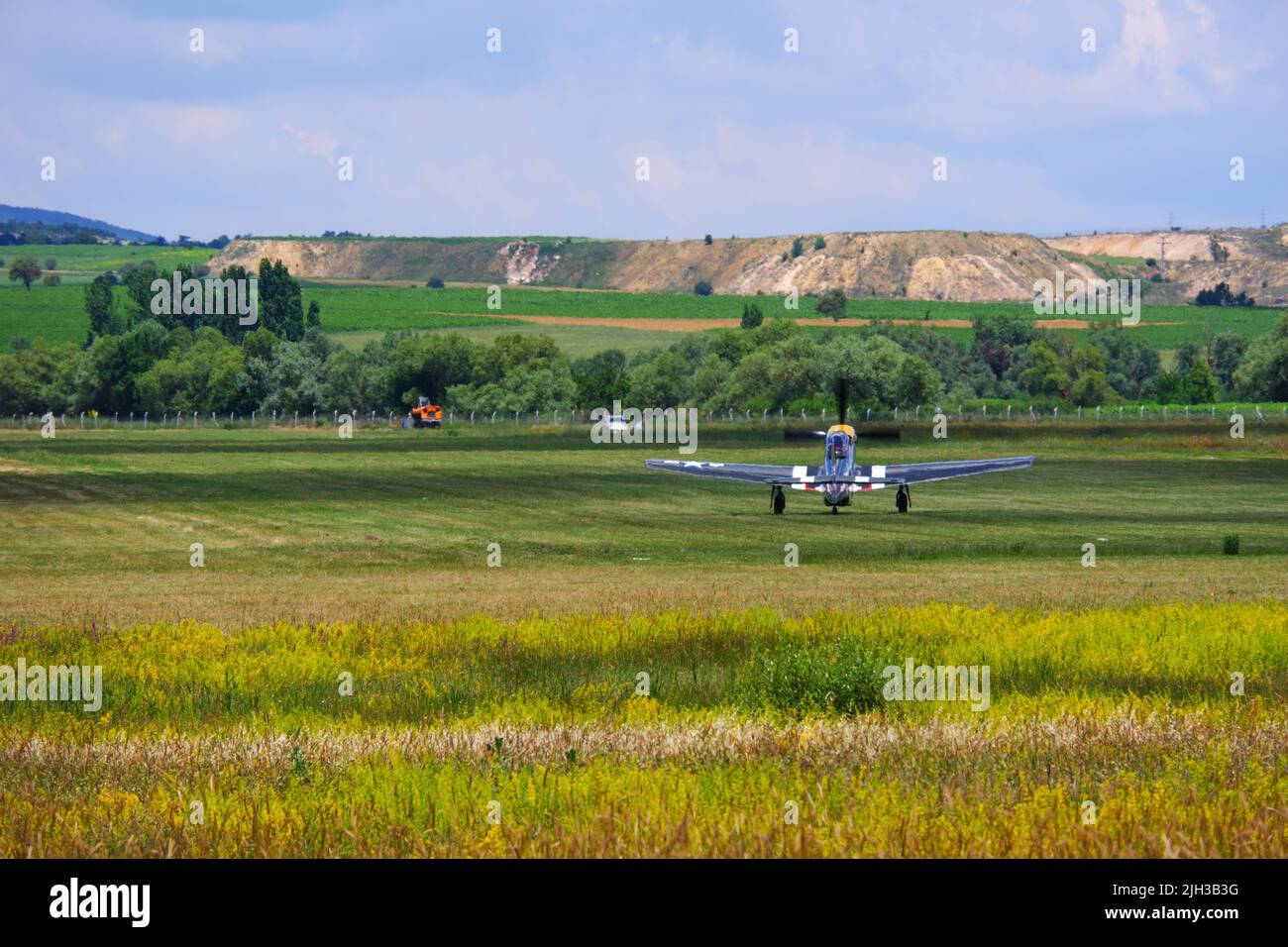 Petit avion partant de la piste d'herbe vers les collines Banque D'Images