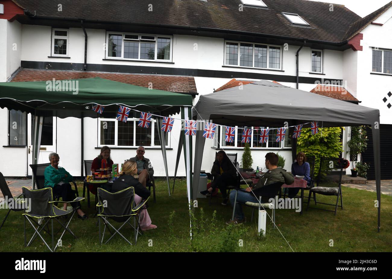 Street Party personnes assises sous les belvédères dans le jardin avant célébrant la reine Elizabeth II Platinum Jubilee Surrey Angleterre Banque D'Images