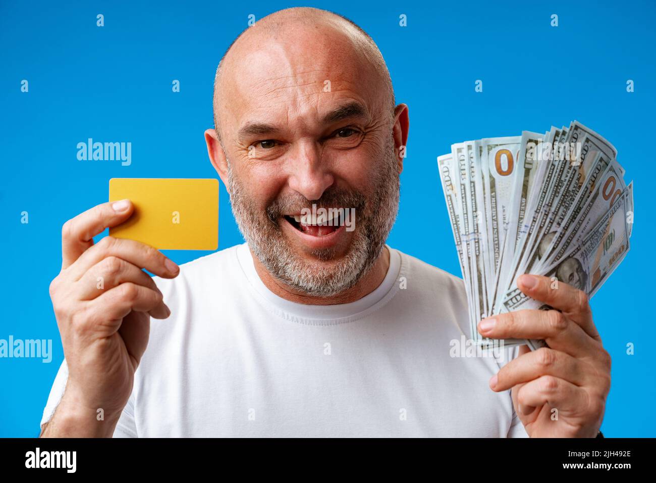 Portrait de l'homme surpris tenant des factures de dollars et de carte de crédit sur fond bleu Banque D'Images