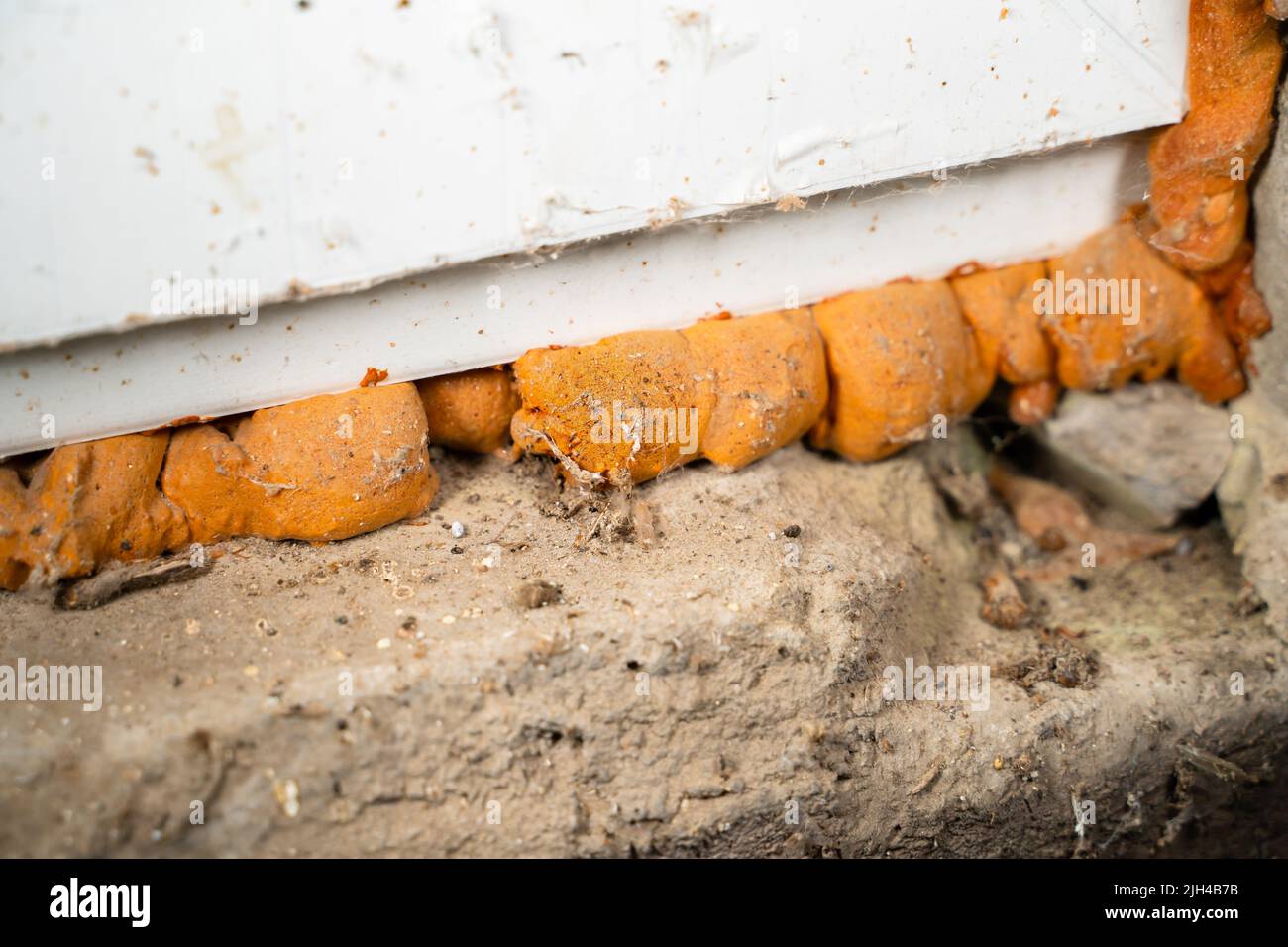 Vieille mousse de polyuréthane orange entre le mur et la fenêtre en plastique gros plan Banque D'Images