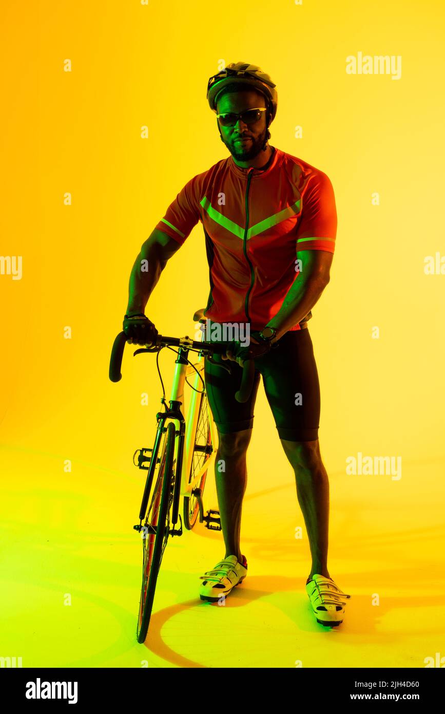 Image verticale d'un cycliste afro-américain regardant la caméra dans un éclairage jaune Banque D'Images
