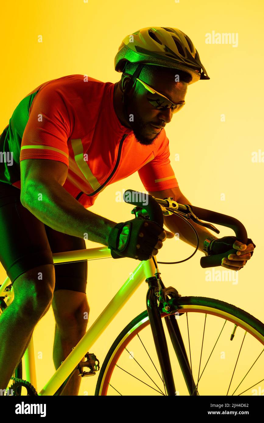 Image verticale du cycliste afro-américain à vélo dans un éclairage jaune Banque D'Images