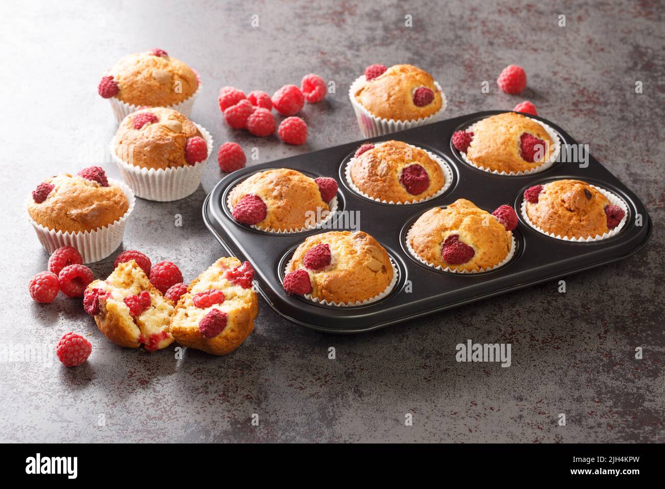 Muffins fraîchement cuits avec framboises et chocolat blanc dans un moule à muffins sur la table. Horizontale Banque D'Images