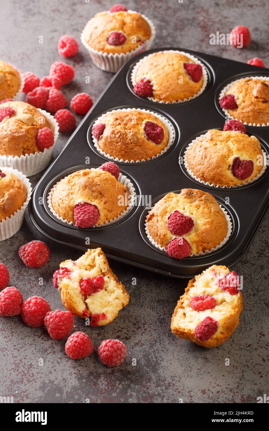 Muffins d'été aux framboises au chocolat blanc en gros plan dans un moule à muffins sur la table. Verticale Banque D'Images