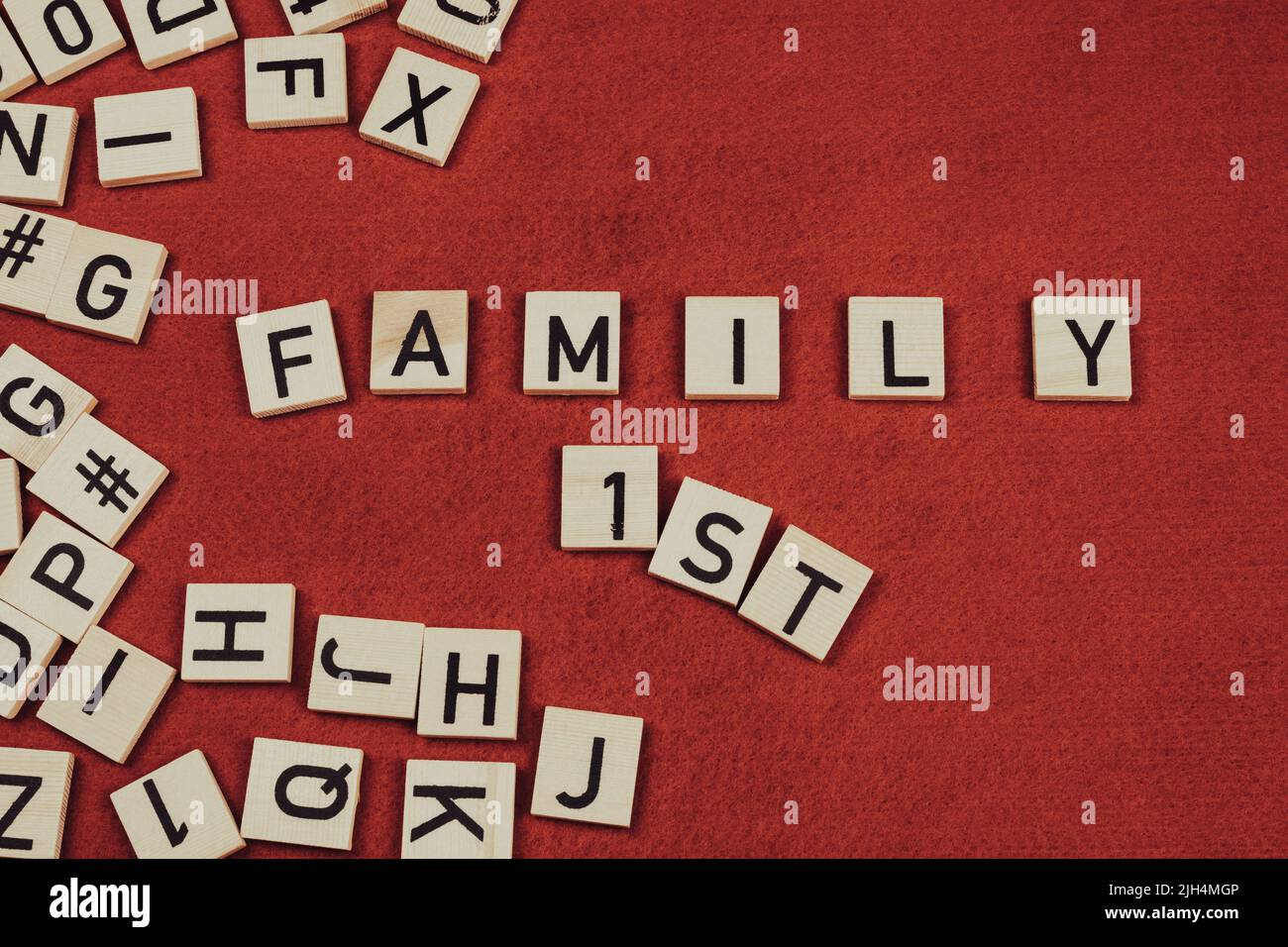 Phrase 'Family 1st' composée de carreaux de bois avec des lettres sur fond de feutre rouge Banque D'Images