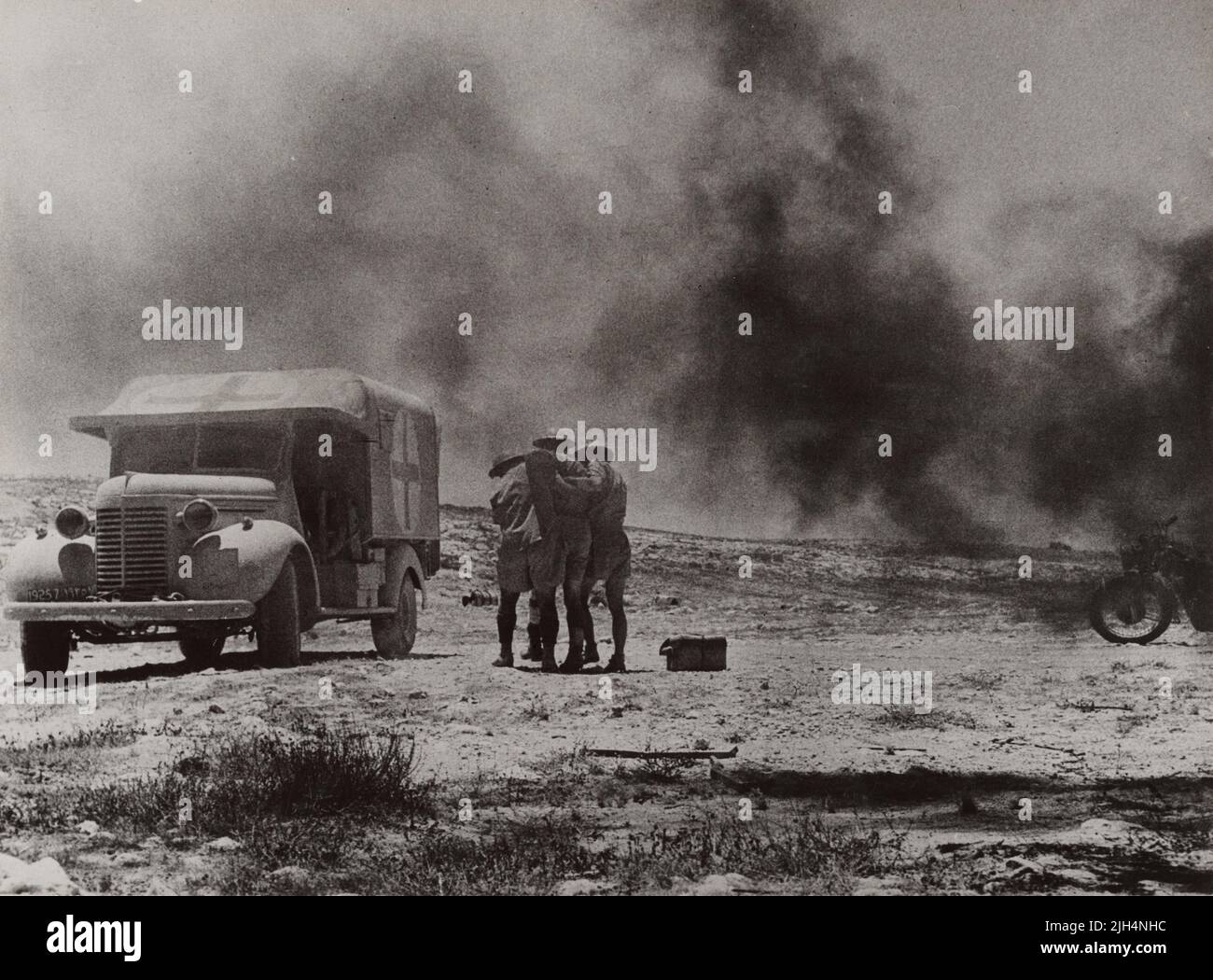 Une photo d'époque vers 1941 montrant deux médecins du Royal Army Medical corps aidant un soldat blessé à une ambulance de campagne peinte par une Croix-Rouge après que les forces de l'axe aient attaqué un convoi médical dans le désert occidental en Afrique du Nord Banque D'Images
