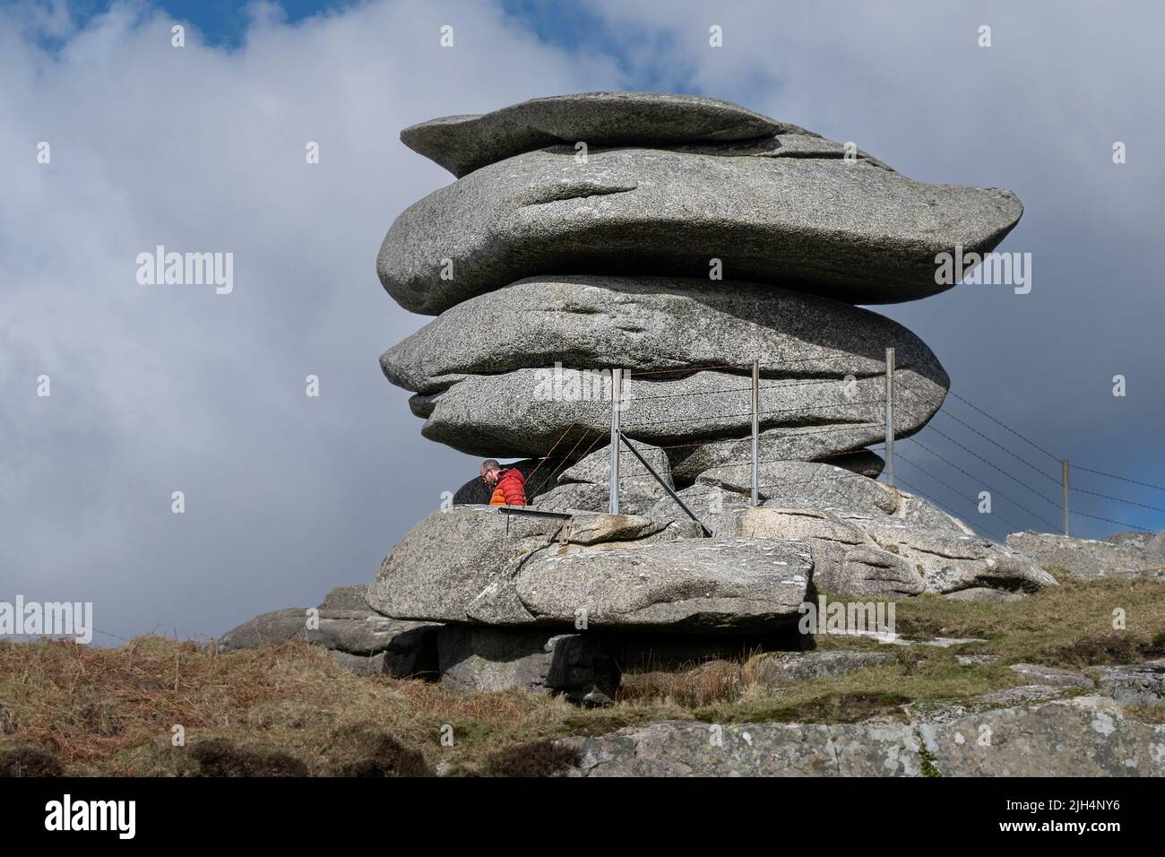 Une personne qui marche sous l'immense pile de roches de granit formée par l'action glaciaire sur la colline de Stowes sur la Moor de Bodmin en Cornouailles. Banque D'Images