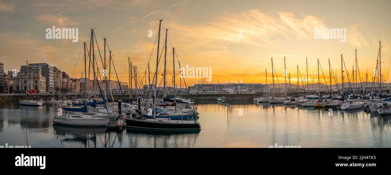 Atardecer en el puerto deportivo de Gijón, con los colores de los reflejos en el agua de los barcos, edificios y cielo, Asturias España Banque D'Images