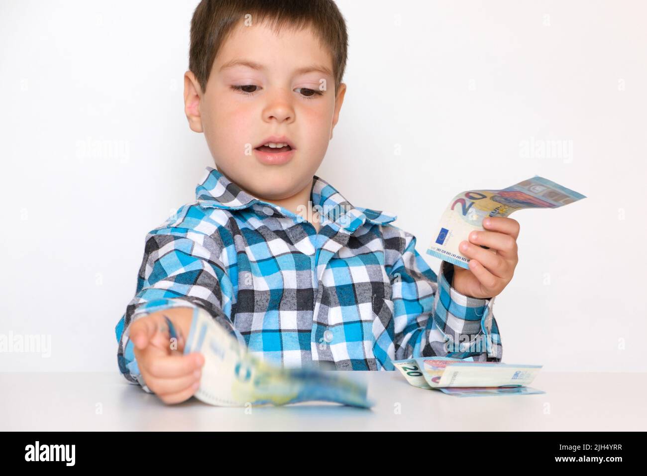 Un garçon de 4 ans compte de l'argent, tient des euros entre ses mains. Enseigner aux enfants la littératie financière, de l'argent de poche. Banque D'Images
