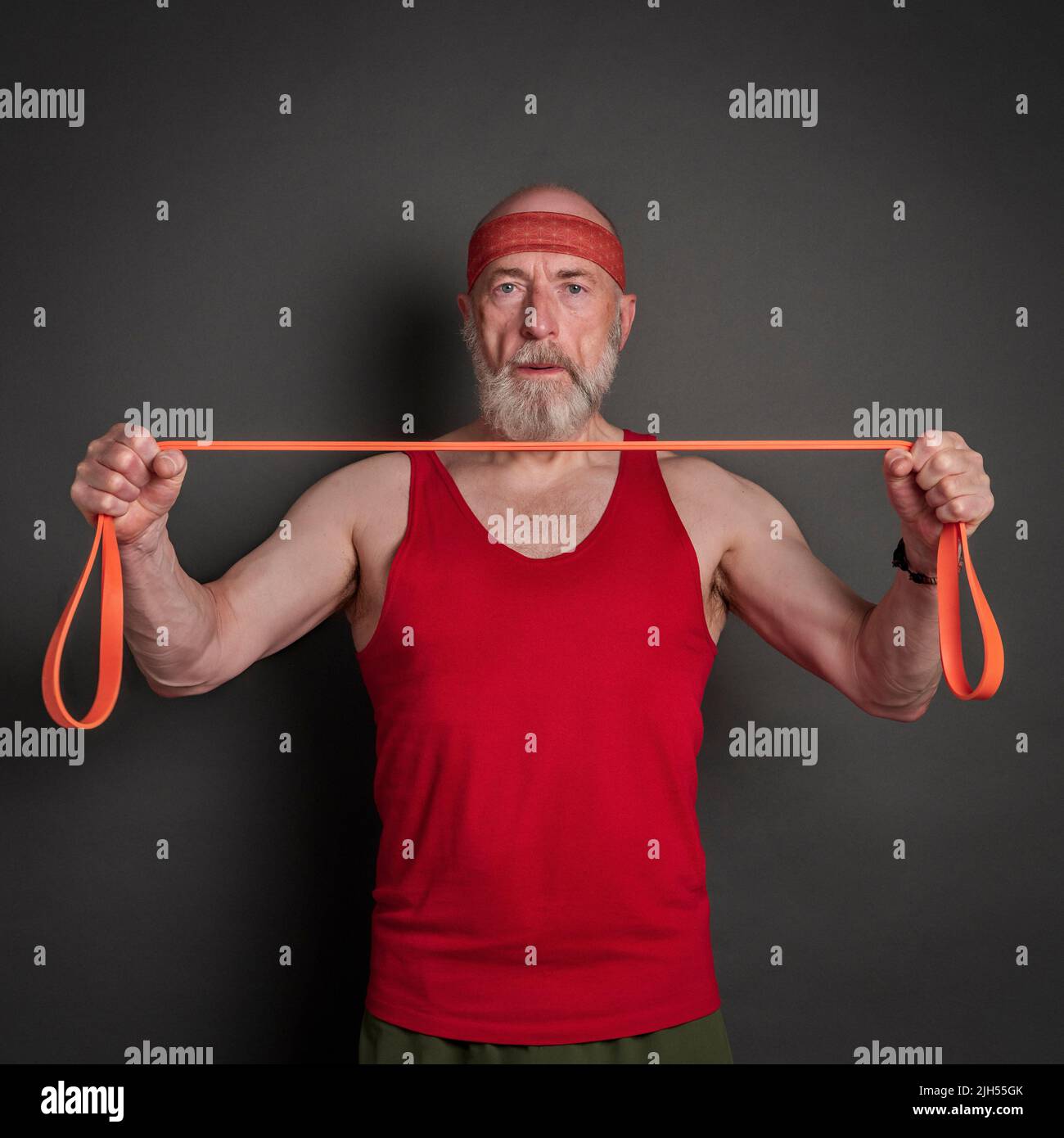 portrait de la tête et de l'épaule de l'homme âgé (fin 60s) s'exerçant avec la bande de résistance, forme physique au-dessus de 60 concept Banque D'Images