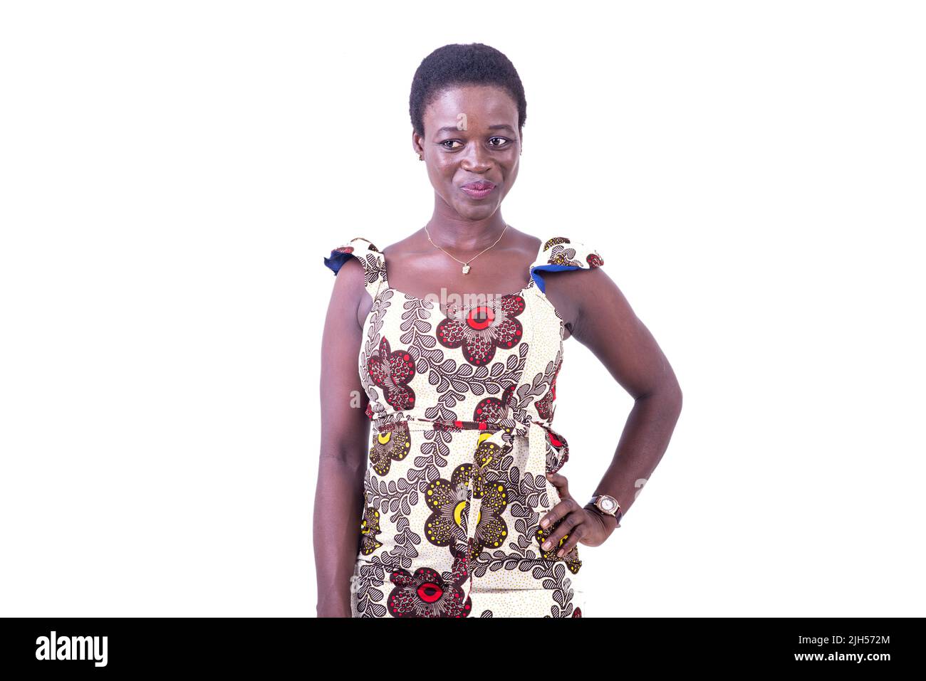 une belle jeune femme africaine en robe en toile de longe debout sur fond blanc regardant la caméra sourire Banque D'Images