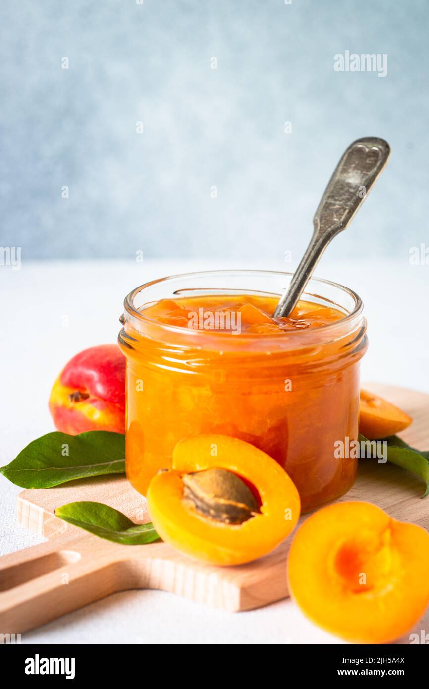 Confiture d'abricot dans un pot en verre à la table blanche. Banque D'Images