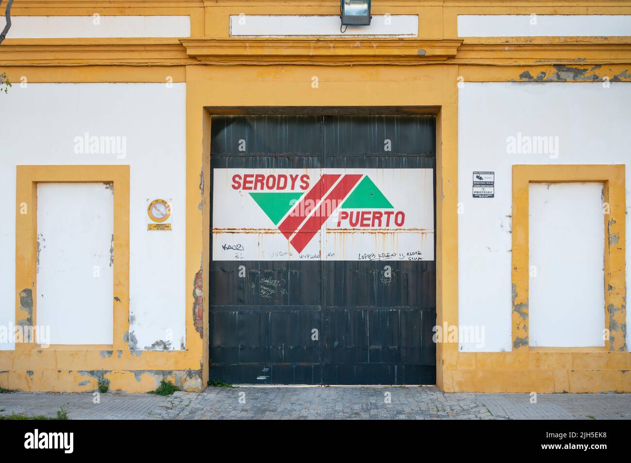 Un serodys Puerto cash et porte sur une porte d'un ancien entrepôt de sherry à Puerto Santa Maria Espagne sur un bâtiment jaune et blanc Banque D'Images