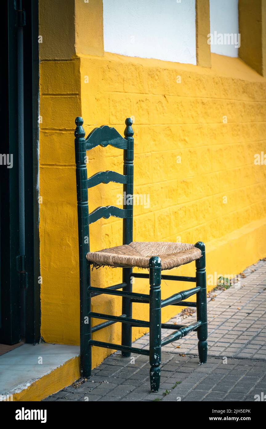 Une chaise à l'extérieur d'un ancien entrepôt de sherry et bodega peint en jaune, par Gutierrrez Colosia à Puerto de Santa Maria Espagne Banque D'Images