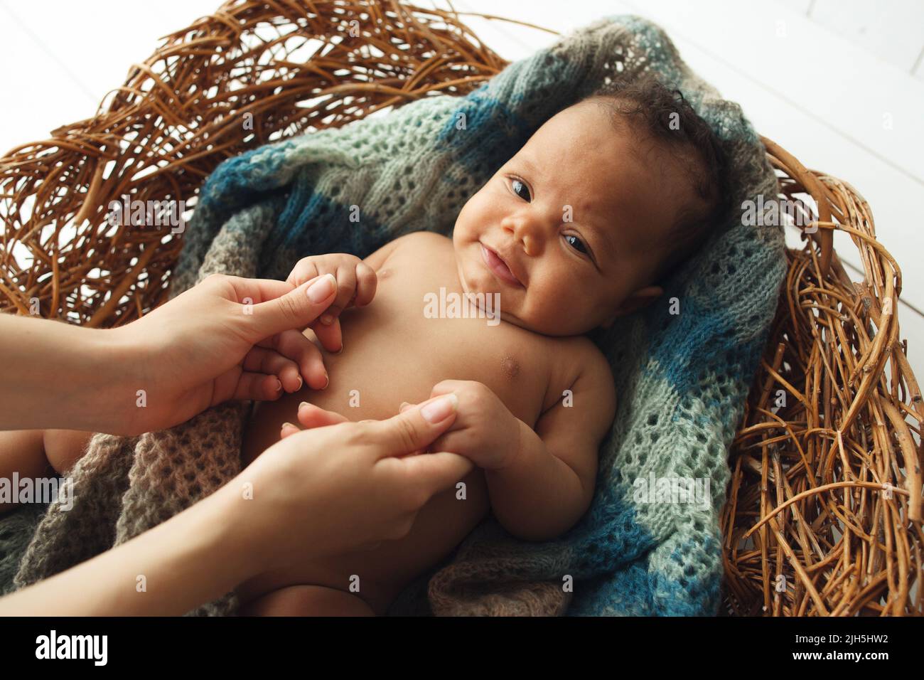 Bébé mignon tenant les mains de maman dans le berceau Banque D'Images