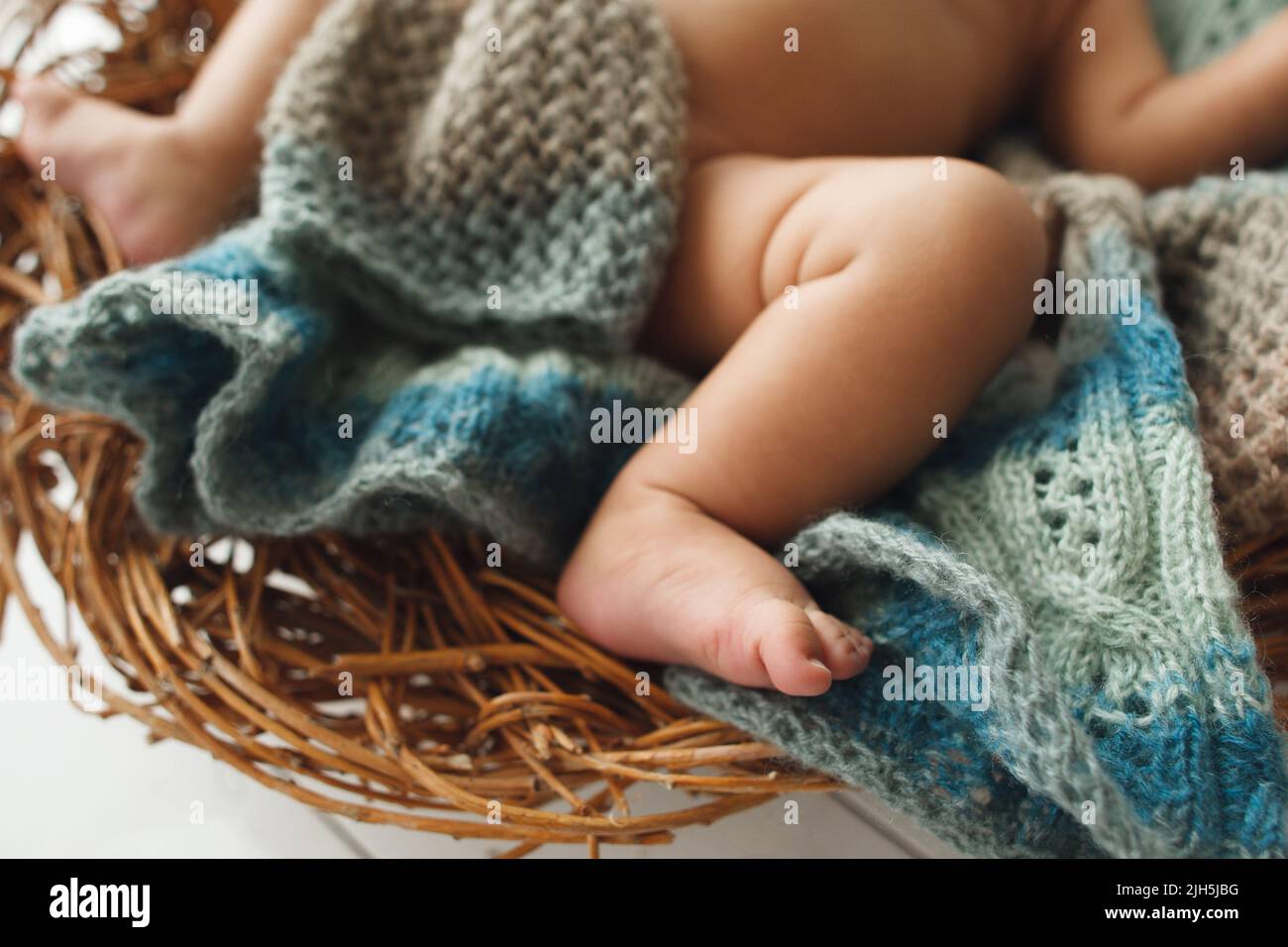 Pieds de bébé allongé sur un berceau en osier en gros plan Banque D'Images