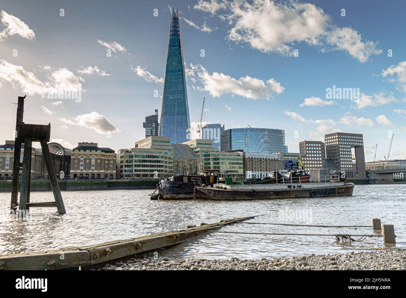 Une vue à angle bas sur la Tamise vers le Shard depuis la rive nord avec des barges amarrées au milieu de la rivière. Banque D'Images