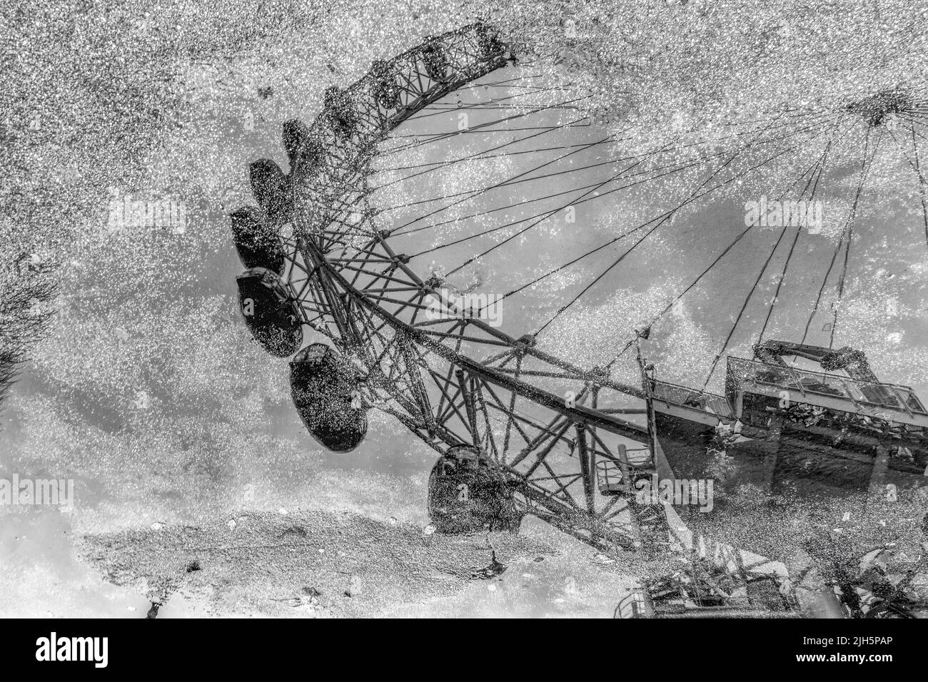 Image en noir et blanc du London Eye reflétée dans une flaque Banque D'Images