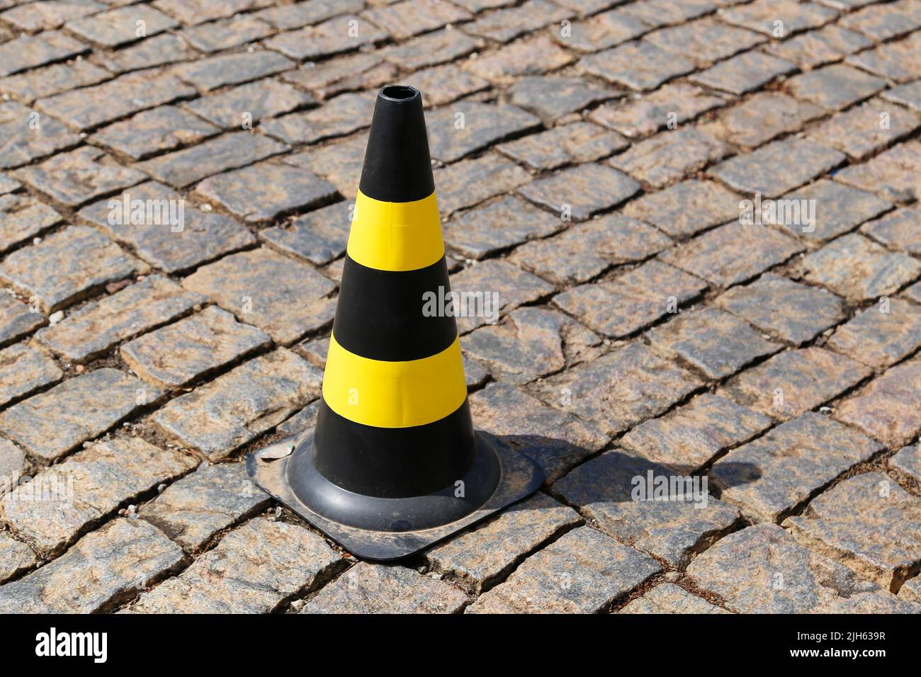 feu de signalisation de couleur jaune et noire, plastique dur, sur la voie publique en pierre Banque D'Images