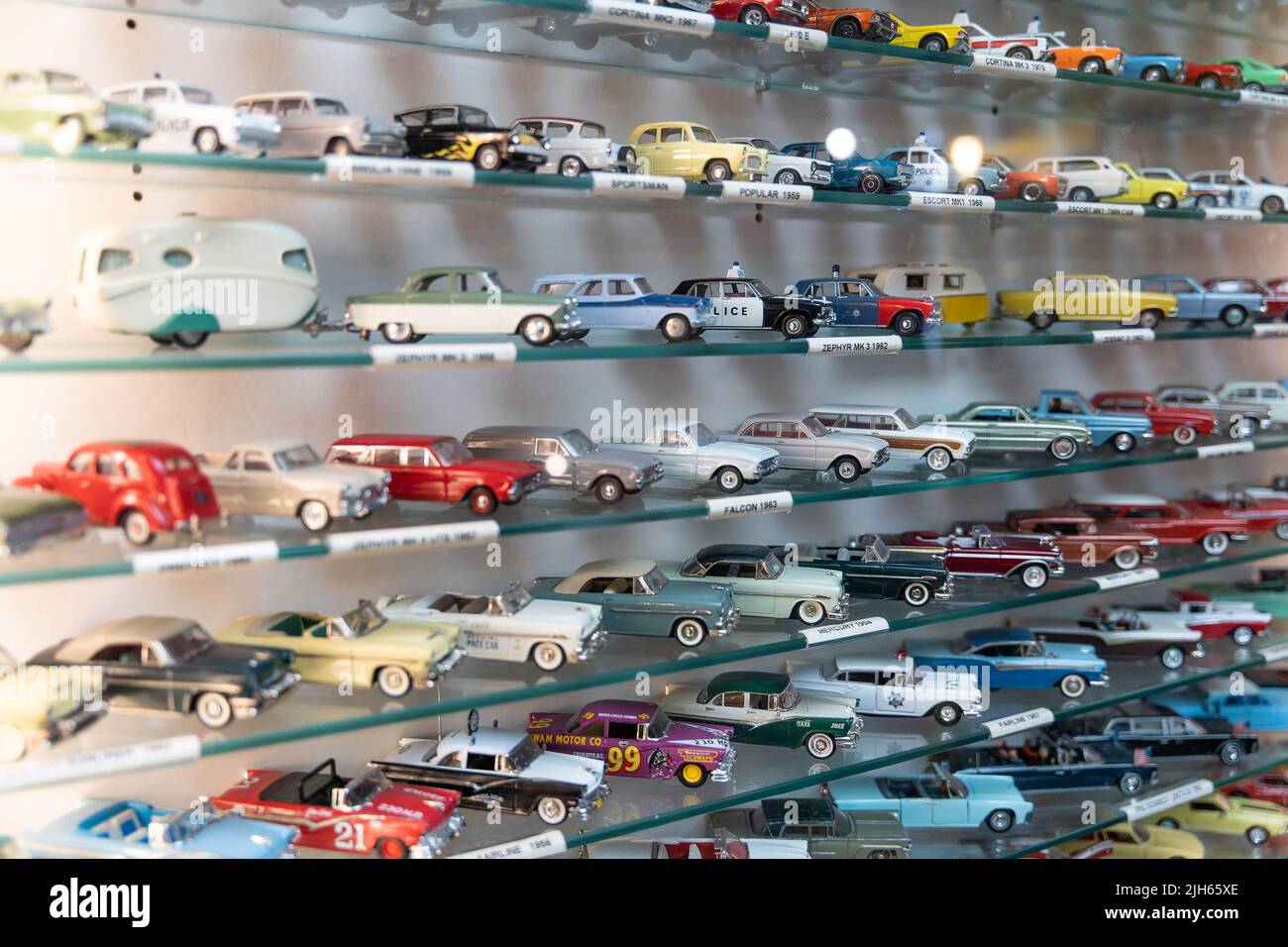 Collection de voitures jouets vintage exposées sur des étagères en verre dans des rangées organisées Banque D'Images