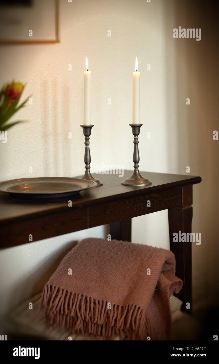 Bougies allumées élégantes et décoratives sur une table en bois à la maison. Décor tissé de jeté et maison pour l'arôme, bon parfum et pour réchauffer une pièce. Confortable Banque D'Images