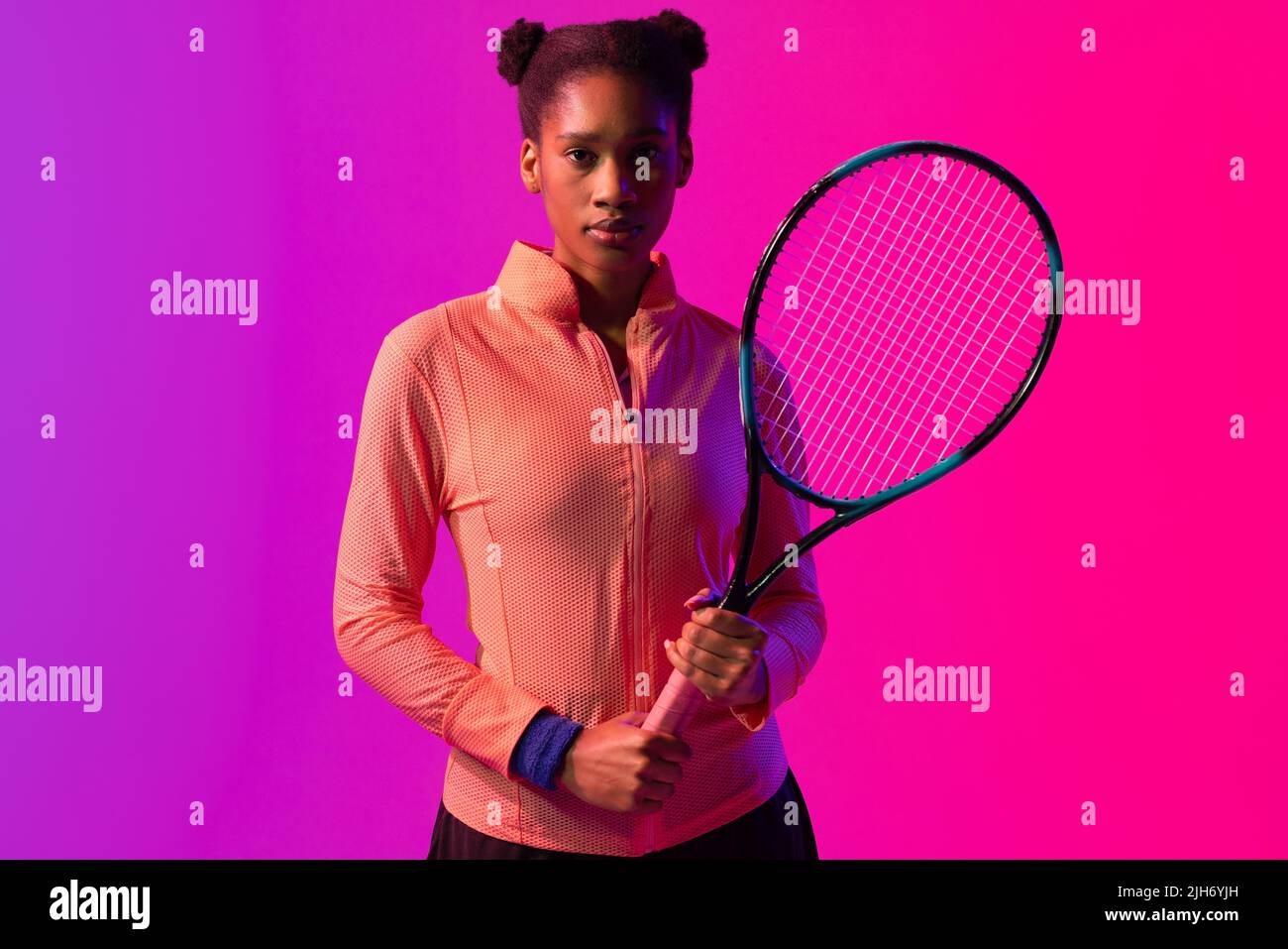 Image d'une joueuse de tennis afro-américaine avec raquette dans un éclairage rose fluo Banque D'Images