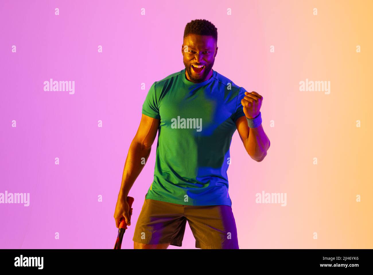 Image d'un joueur de tennis afro-américain réussi dans un éclairage violet et jaune Banque D'Images