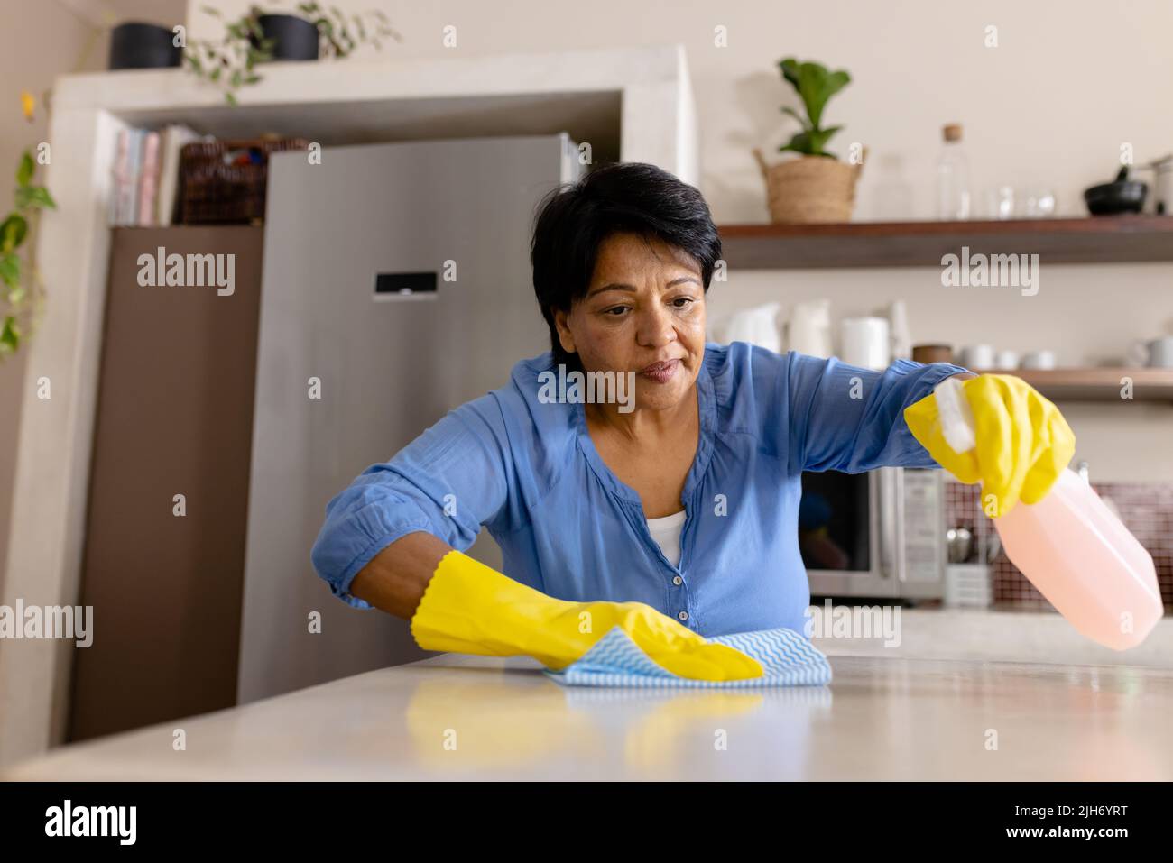 Vue à angle bas de biracial femme mûre portant des gants nettoyage cuisine île avec un chiffon, copier l'espace Banque D'Images