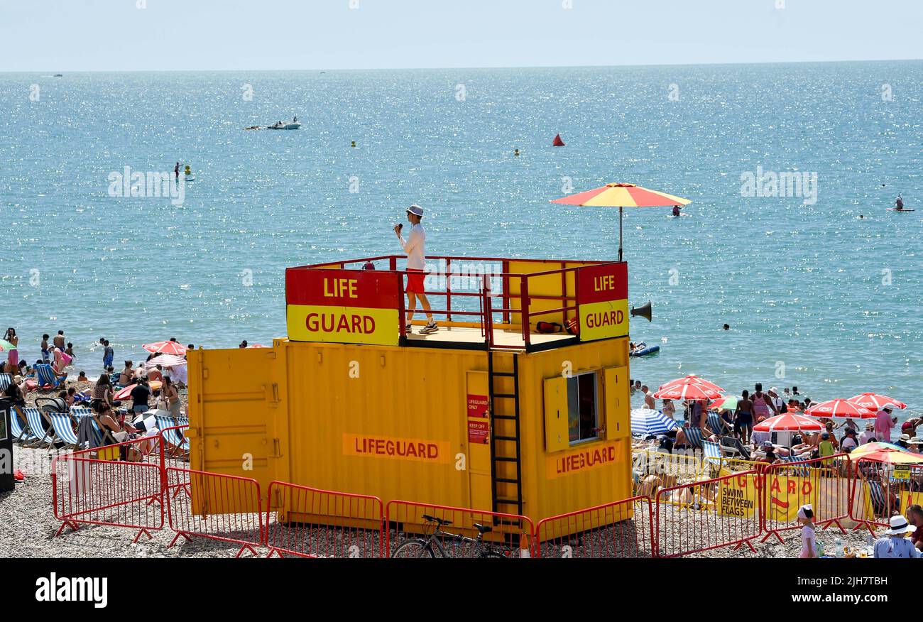 Brighton Royaume-Uni 16th juillet 2022 - Un agent de protection de la vie surveille la plage de Brighton qui est bourrée de soleil par les foules aujourd'hui, mais un avertissement de temps rouge extrême a été émis pour la partie tôt de la semaine prochaine : Credit Simon Dack / Alamy Live News Banque D'Images