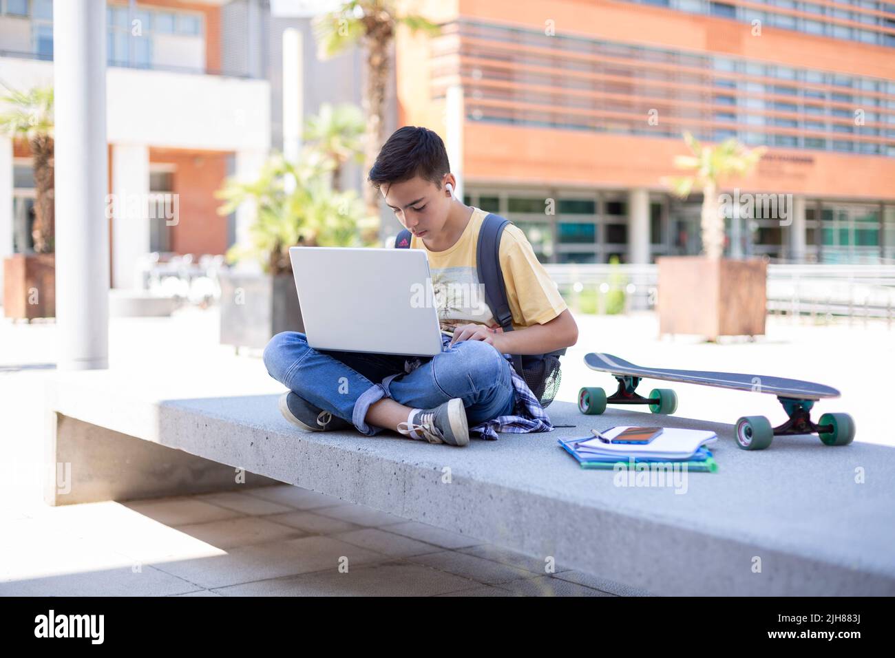 Étudiant de lycée de garçon caucasien utilisant un ordinateur portable à l'extérieur. Espace pour le texte. Banque D'Images