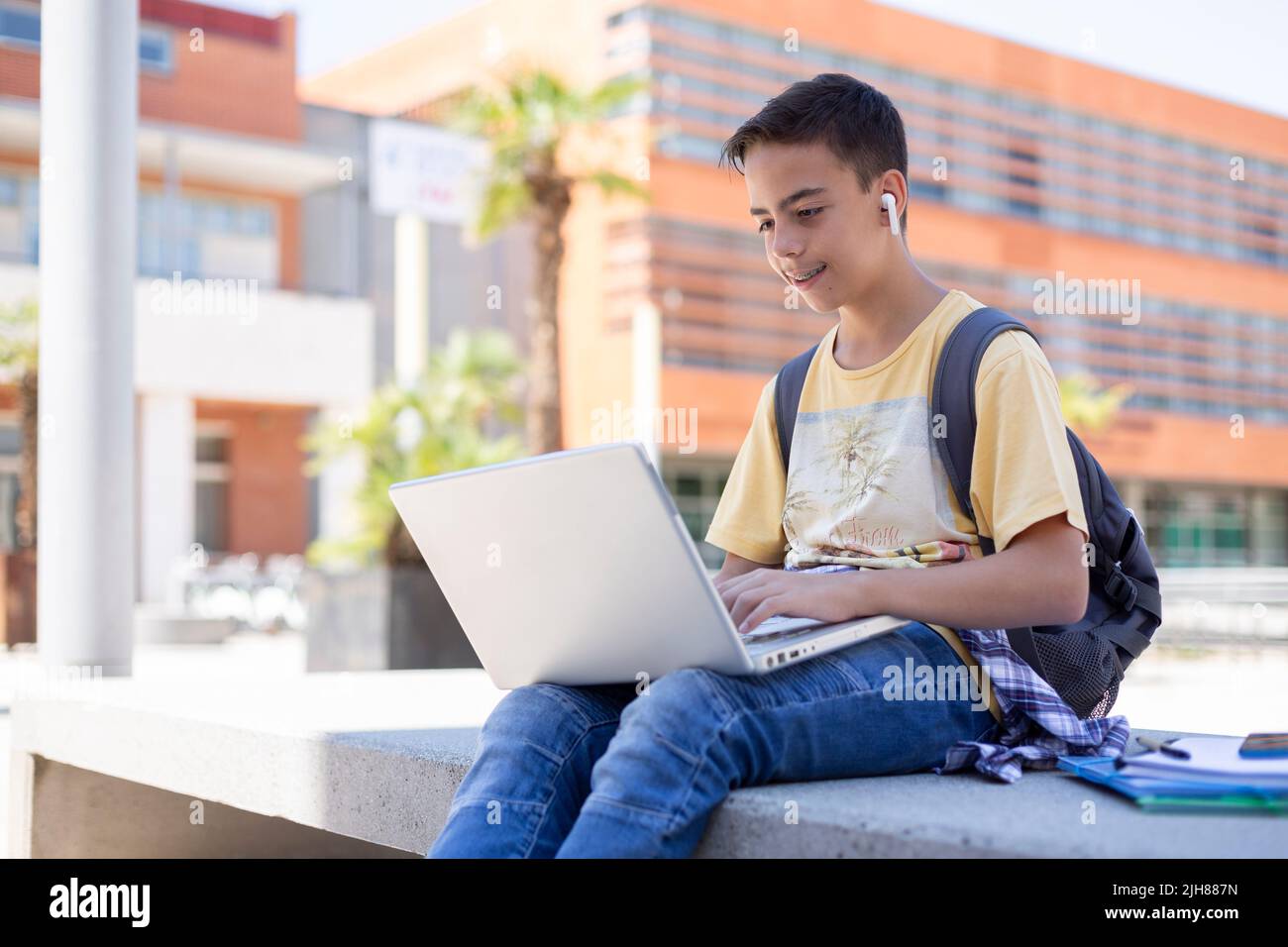 Souriant garçon caucasien étudiant avec un ordinateur portable à l'extérieur. Enseignement secondaire. Espace pour le texte. Banque D'Images