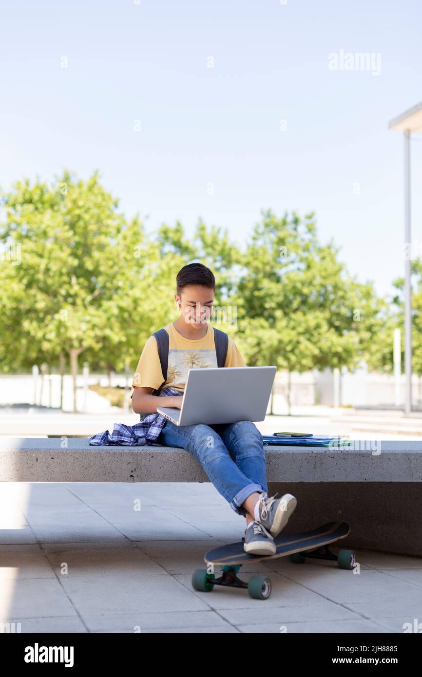 Adolescent de race blanche utilisant un ordinateur portable à l'extérieur. Retour à l'école. Espace pour le texte. Banque D'Images