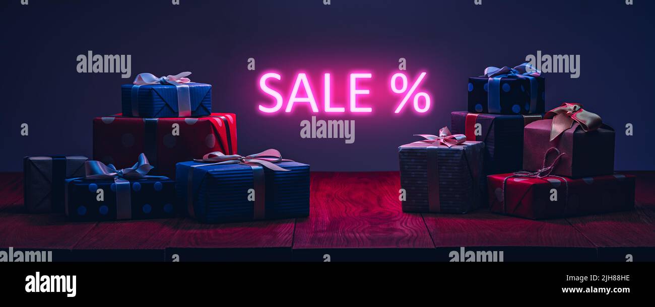 Boîtes-cadeaux sur la table avec éclairage au néon. Concept de vente Banque D'Images