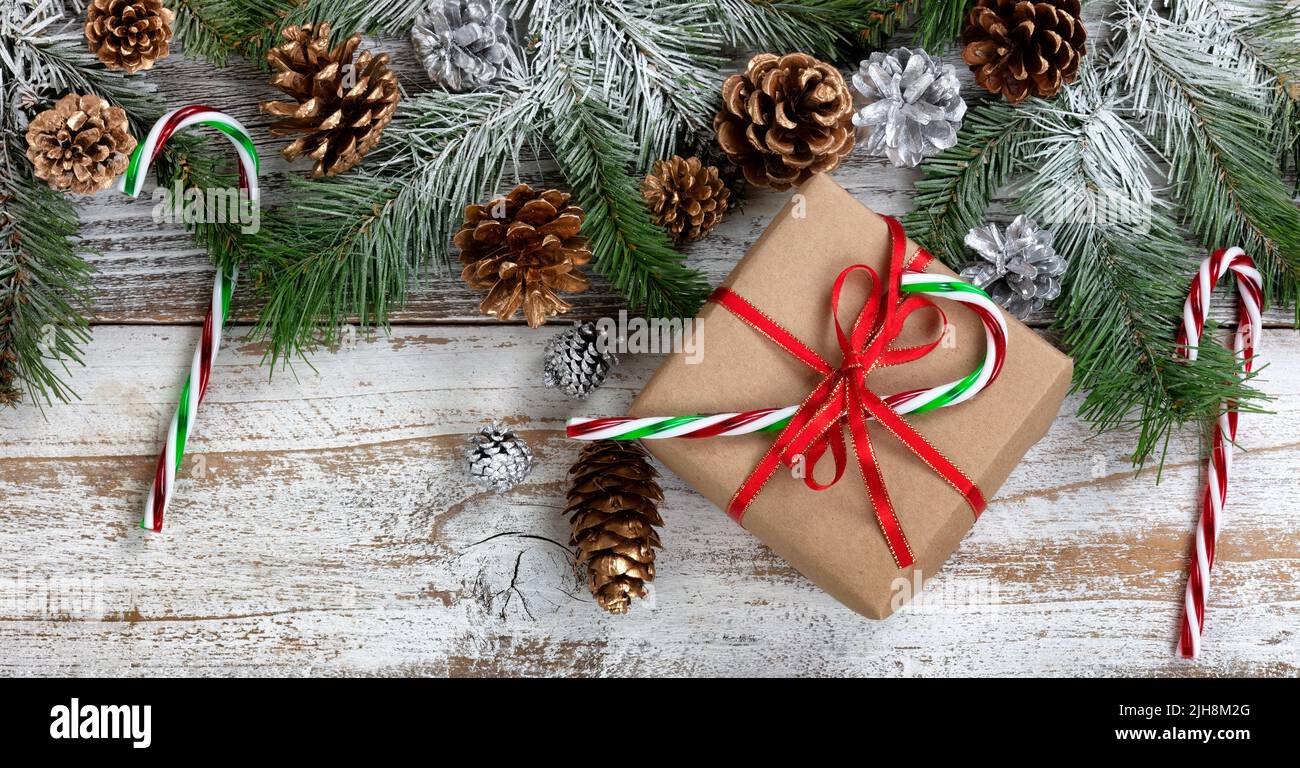 Concept de Noël et de nouvel an avec branches de sapin couvertes de neige, boîte-cadeau, Cannes de bonbons et cônes de pin d'or argenté sur bois rustique blanc Banque D'Images