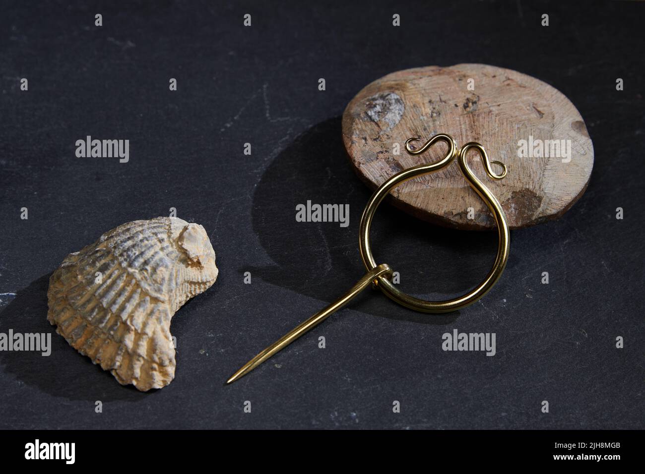 Les beaux bracelets dorés de l'époque romaine avec des motifs sur une surface noire avec ombre et un seashell Banque D'Images